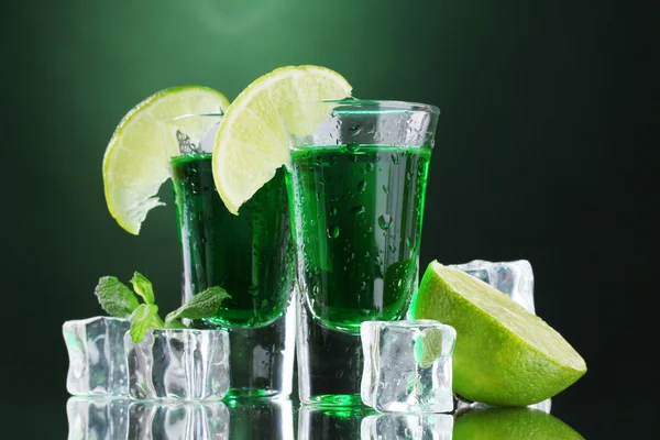 Dos vasos de absenta, lima y hielo sobre fondo verde —  Fotos de Stock
