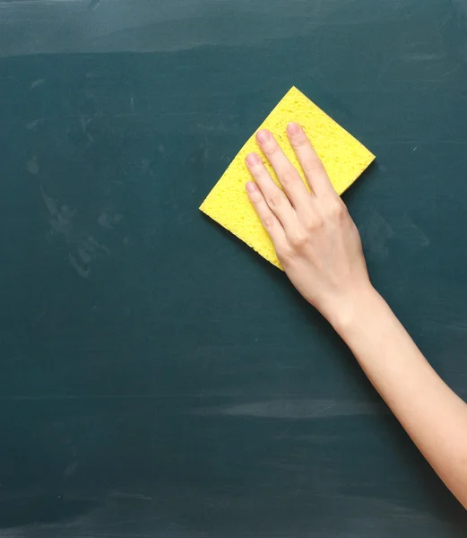 Hand met een gele spons reinigen van het schoolbord — Stockfoto