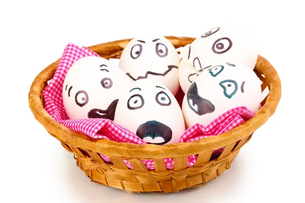 Белые яйца со смешными лицами в корзине изолированы на белом — стоковое фото