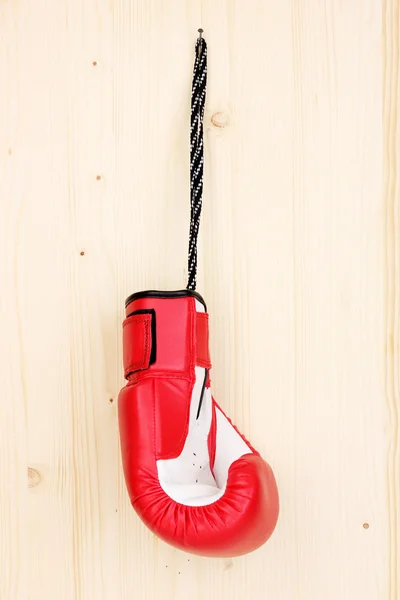 Red boxing glove hanging on wooden background — Stock Photo, Image