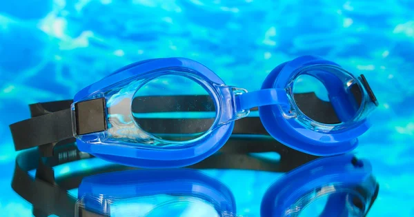 Óculos de natação azuis com gotas no fundo azul do mar — Fotografia de Stock