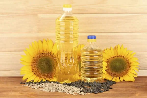 Sonnenblumenöl und Sonnenblumen auf Holz Hintergrund — Stockfoto