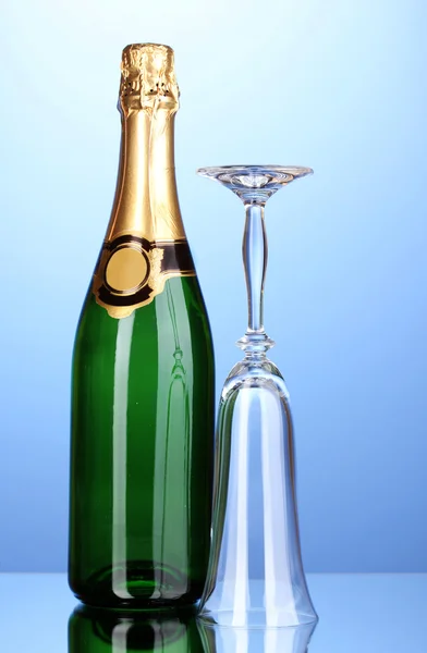 Bir şişe şampanya ve mavi zemin üzerine kadehi — Stok fotoğraf
