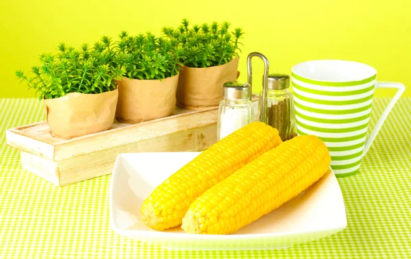 Gekookte maïs en bloemen op een groene achtergrond — Stockfoto