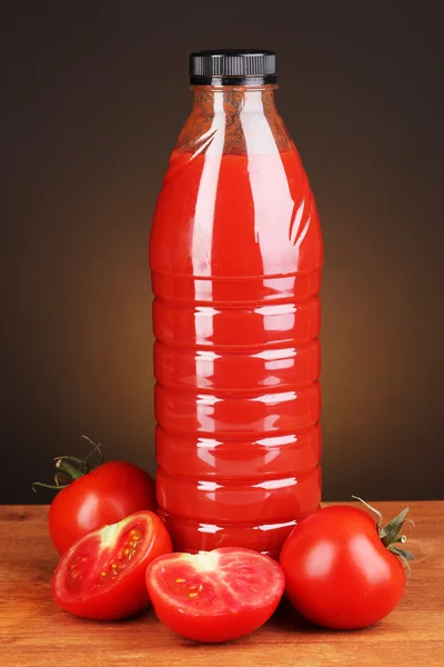Jugo de tomate en botella sobre mesa de madera sobre fondo marrón — Foto de Stock