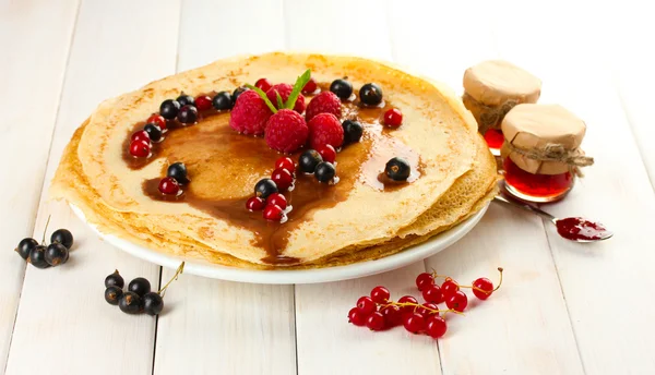 Delicious pancakes with berries and jam on plate on wooden table — Stock Photo, Image