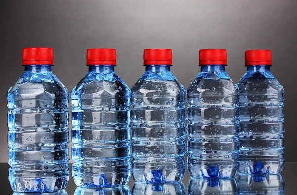 Plastic flessen water op grijze achtergrond — Stockfoto