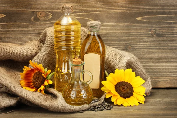 Олія в пляшках, соняшниках і насіннях, на дерев'яному фоні — стокове фото