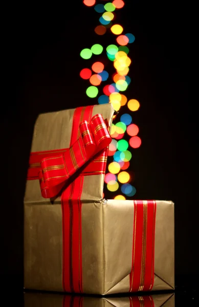 Открытый золотой подарочный коробок с боке фон на черном — стоковое фото