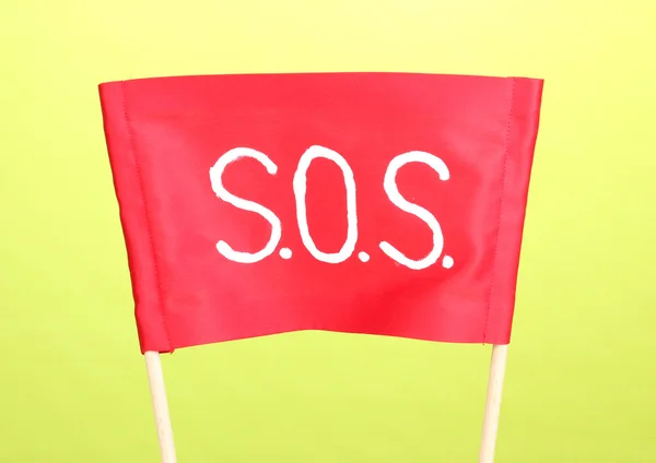 Signal SOS écrit sur tissu rouge sur fond vert — Photo
