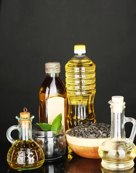 Azeite e óleo de girassol nas garrafas e pequenos decantadores isolados em fundo preto close-up — Fotografia de Stock