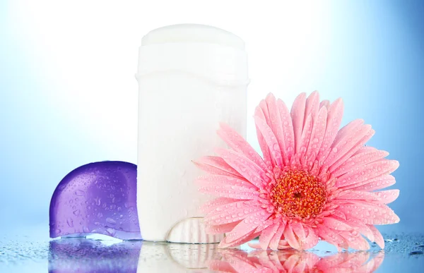 Deodorant with flower on blue background — Stock Photo, Image