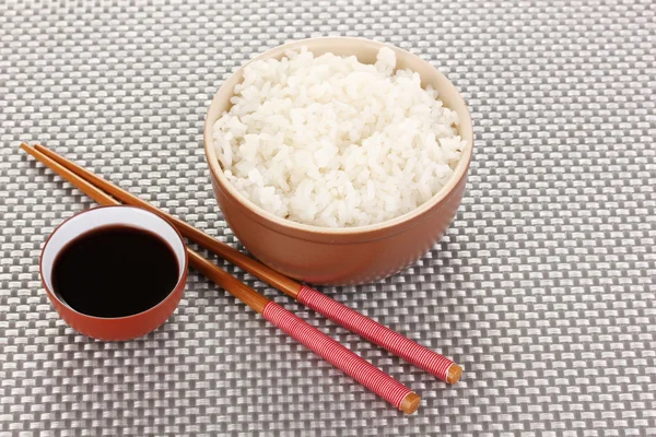 Ciotola di riso e bacchette su tappetino grigio — Foto Stock