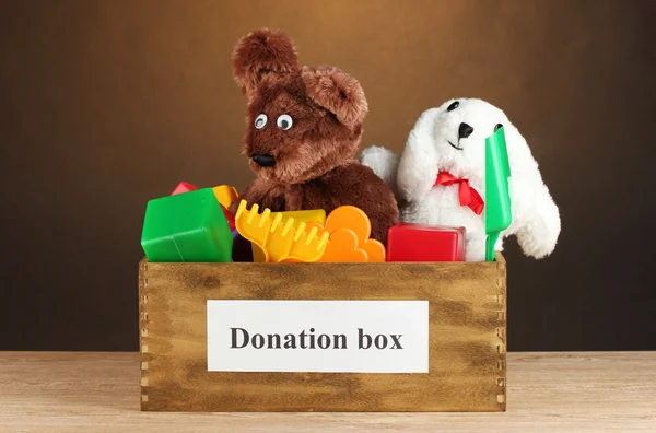 Caixa de doação com brinquedos infantis em fundo marrom close-up — Fotografia de Stock