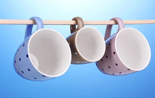 stock image Nice cups hanging on stick on blue background