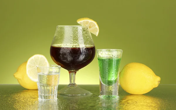 A különböző alkoholtartalmú italok, zöld háttér — Stock Fotó