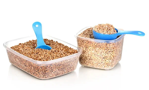 Cucharas de medir y recipientes de plástico con grano aislado en blanco — Foto de Stock