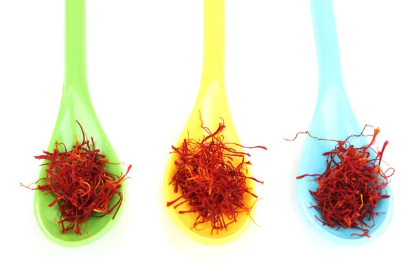 Stigmas of saffron in multicolored spoons on white background close-up — Stock Photo, Image