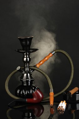 Smoking tools - a hookah, cigar, cigarette and pipe on black background clipart