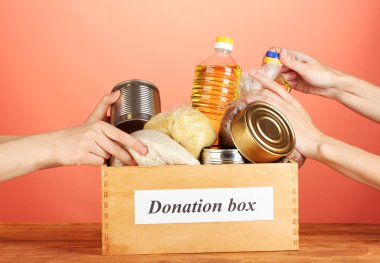 Donation box with food on red background close-up clipart