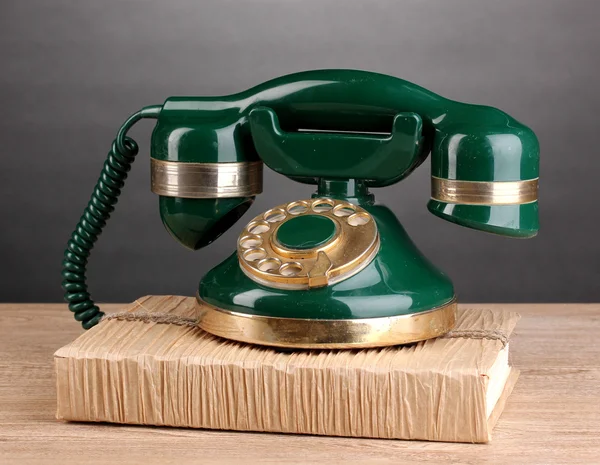 Telefon retro stojący na książki na drewnianym stole na szarym tle — Zdjęcie stockowe
