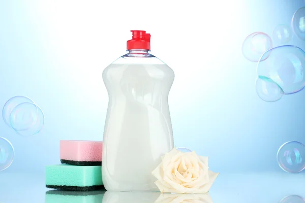 食器洗い液体スポンジと青色の背景色の花 — ストック写真