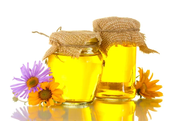 Süßer Honig in Gläsern und Blüten isoliert auf weiß — Stockfoto