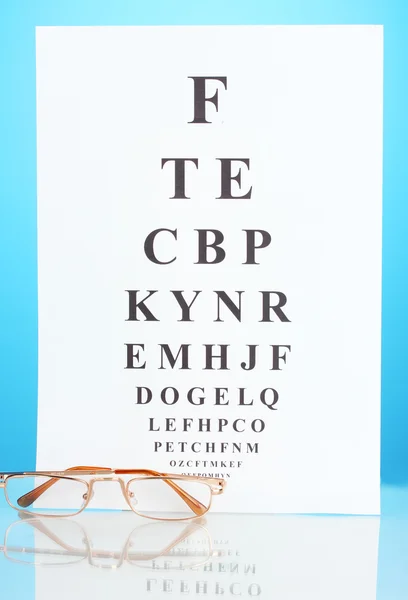 Tabla de pruebas de la vista con gafas en primer plano de fondo azul — Foto de Stock