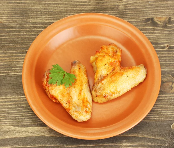 Roasted chicken wings with parsley in the plate on wooden background close-up — Stock Photo, Image