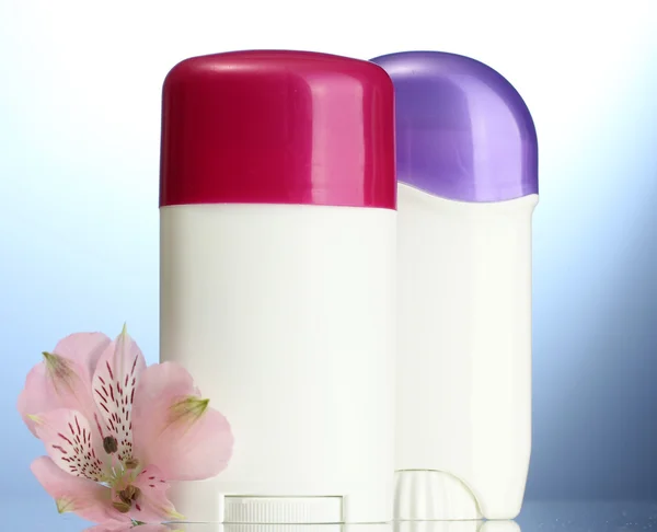 Deodoranty s květem na modrém pozadí — Stock fotografie