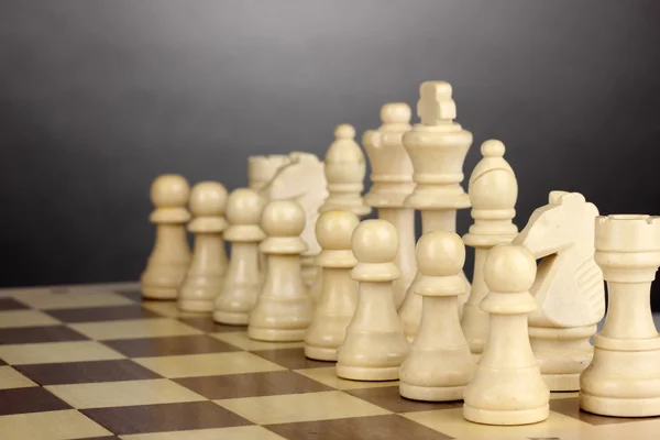 Gri arka plan üzerinde satranç taşları ile satranç masası — Stok fotoğraf