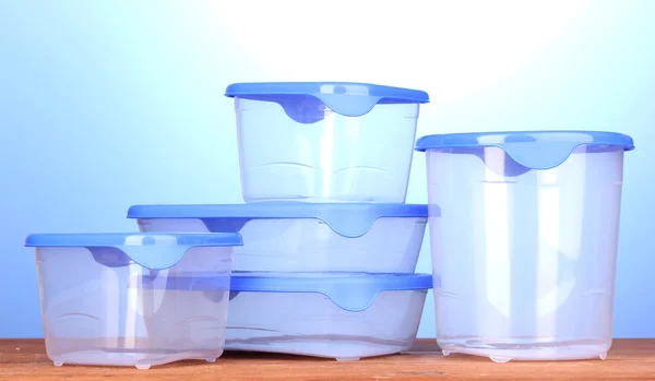 Plastbehållare för mat på träbord på blå bakgrund — Stockfoto
