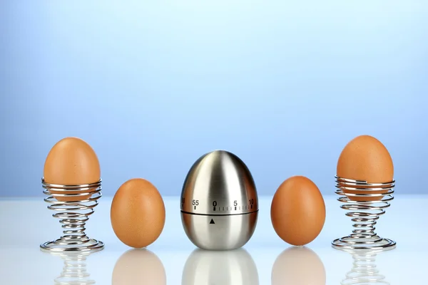 Eieruhr und Eier auf blauem Hintergrund — Stockfoto