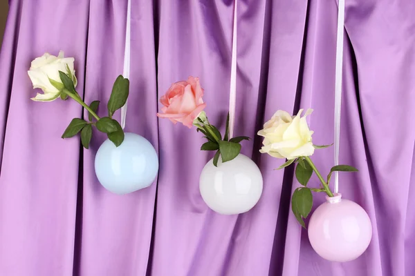Hermosas rosas en jarrones colgando sobre fondo de tela —  Fotos de Stock