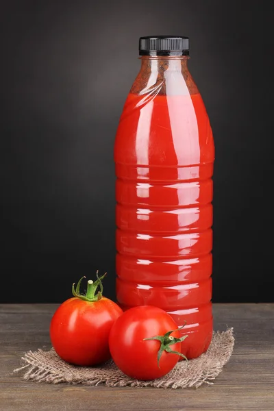Tomato juice in bottle on wooden table on grey background — Stock Photo, Image