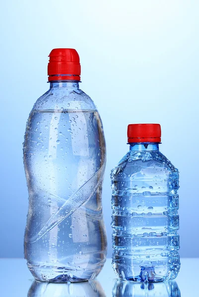 Пластикові пляшки води на синьому фоні — стокове фото