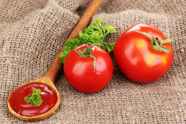 Ketchup and ripe tomatoes on sacking close-up — Stock Photo, Image