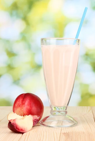 Персикове молоко трясеться на дерев'яному столі на яскравому фоні — стокове фото