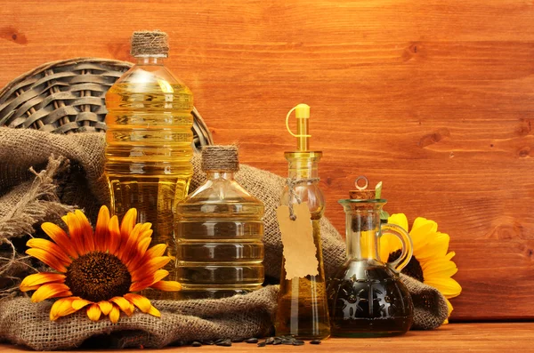 Λάδι σε μπουκάλια, ηλιοτρόπια και σπόρους, σε ξύλινο φόντο — Φωτογραφία Αρχείου