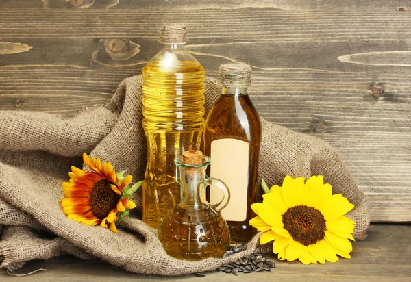 Olej w butelkach, słoneczniki i nasiona, na tle drewniane — Zdjęcie stockowe