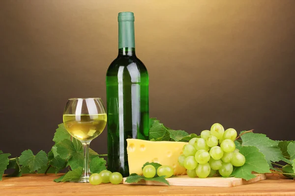 Garrafa de grande vinho com vidro e queijo em mesa de madeira sobre fundo marrom — Fotografia de Stock
