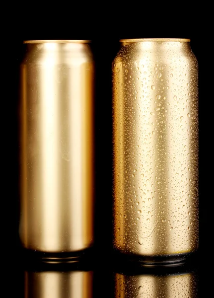 Latas douradas com gotas de água isoladas em preto — Fotografia de Stock
