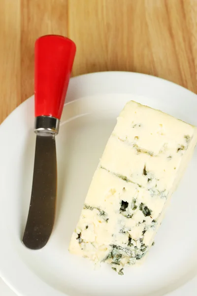 Kaas met schimmel op het kiemgetal en het mes op houten achtergrond close-up — Stockfoto