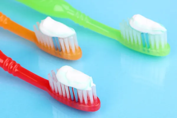 Tandenborstels met plakken op blauwe achtergrond — Stockfoto