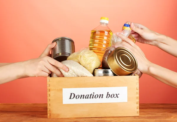Spendenbox mit Lebensmitteln auf rotem Hintergrund in Großaufnahme — Stockfoto