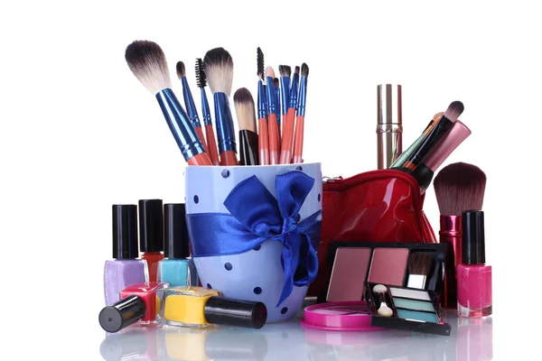 Cepillos de maquillaje en taza y cosméticos aislados en blanco — Foto de Stock