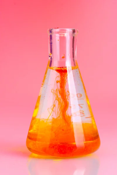 Brilhantemente tinta em um frasco com água sobre fundo rosa — Fotografia de Stock