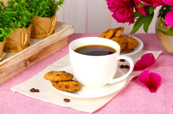 Cup of coffee, cookies and flowers on table in cafe — Stock Photo, Image