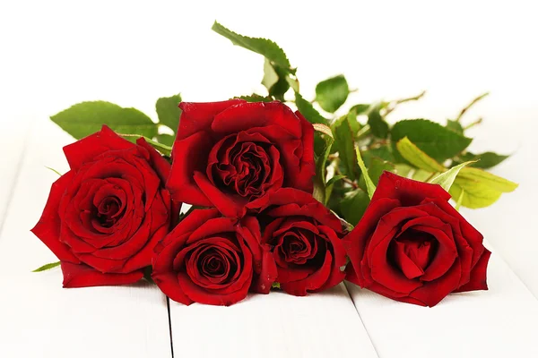 Strauß roter Rosen auf einem weißen Holztisch in Großaufnahme — Stockfoto