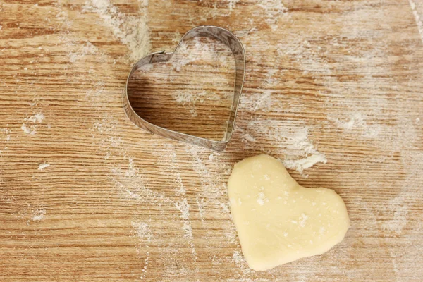 stock image Cutter for the dough to the unbaked biscuits on a wooden table close-up